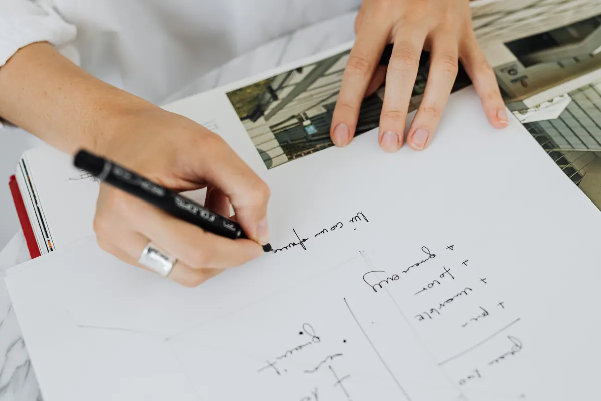 Manos dibujando con un rotulador sobre una lámina de estudio de arquitectura